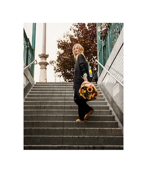 Model steht auf einer Treppe mit Blumenstrauß in der Hand