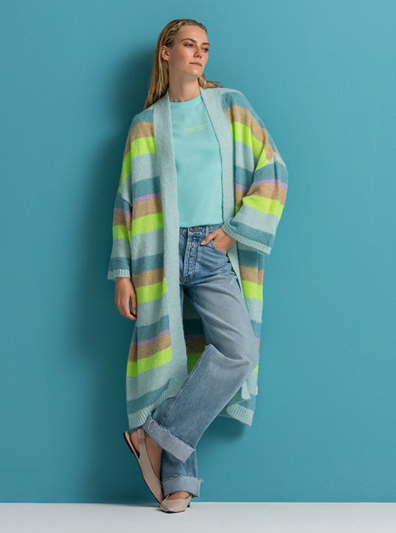 Model steht mit gestreiften long Cardigan vor einer blauen Wand